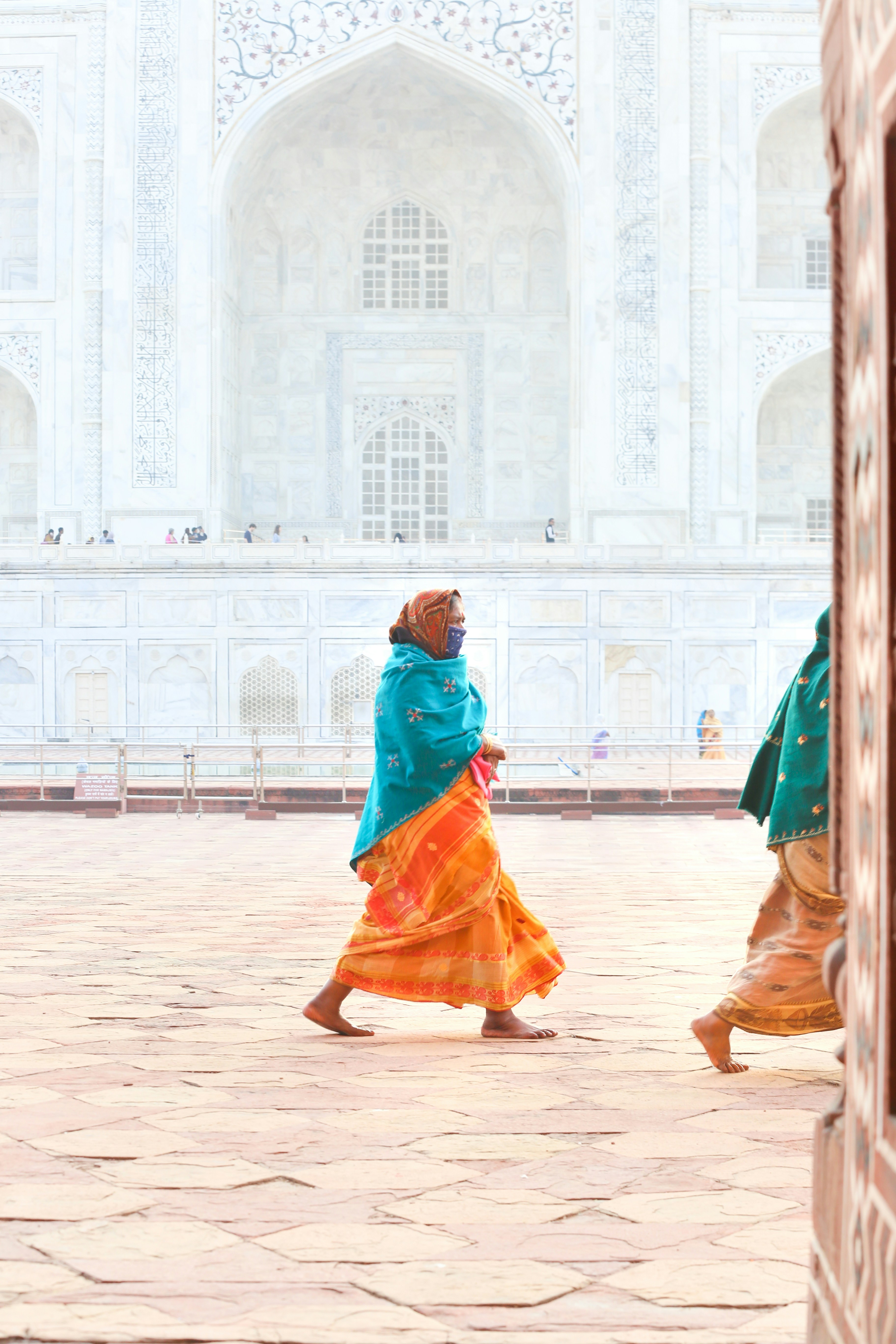 woman in teal dress walking on brown sand during daytime