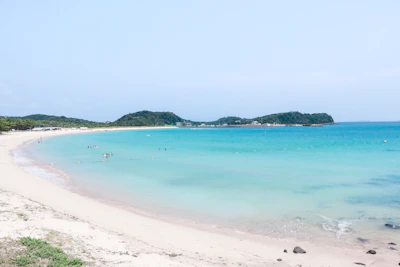 A group of travelers enjoying a serene beach with white sand and turquoise sea.