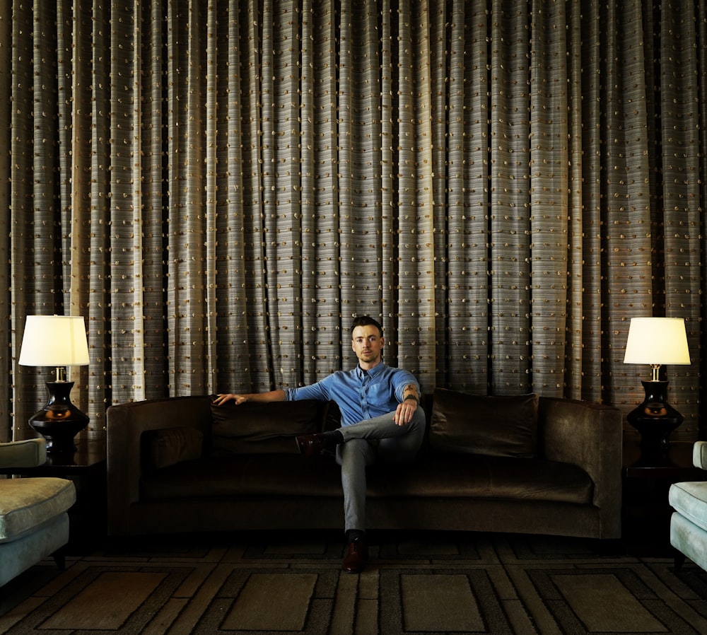 man in blue shirt sitting on couch