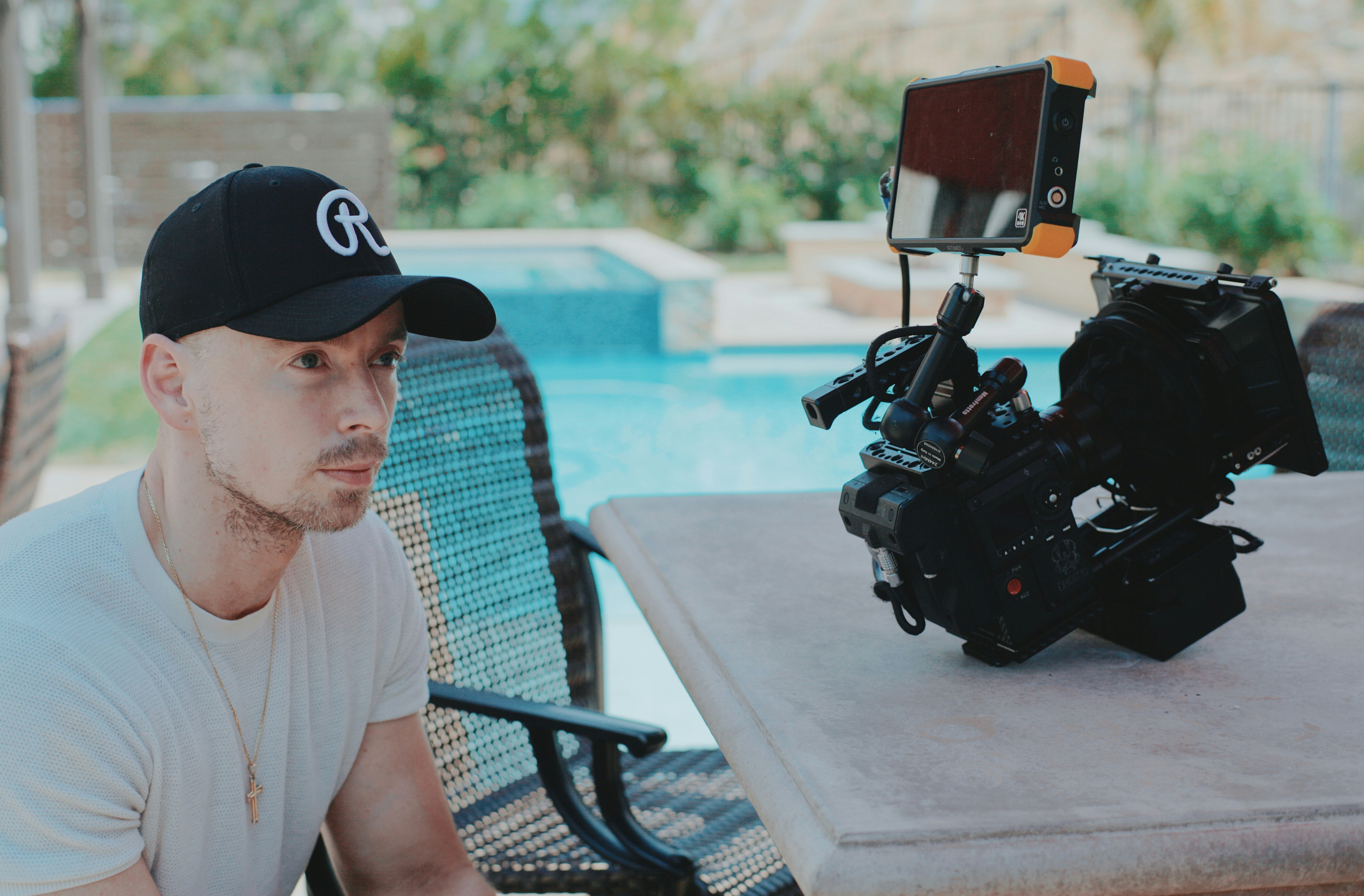 man in white crew neck t-shirt and blue and black fitted cap sitting on black