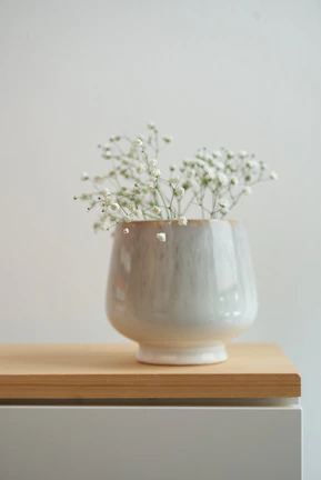 An elegant ceramic vase filled with fresh wildflowers on a minimalist shelf.
