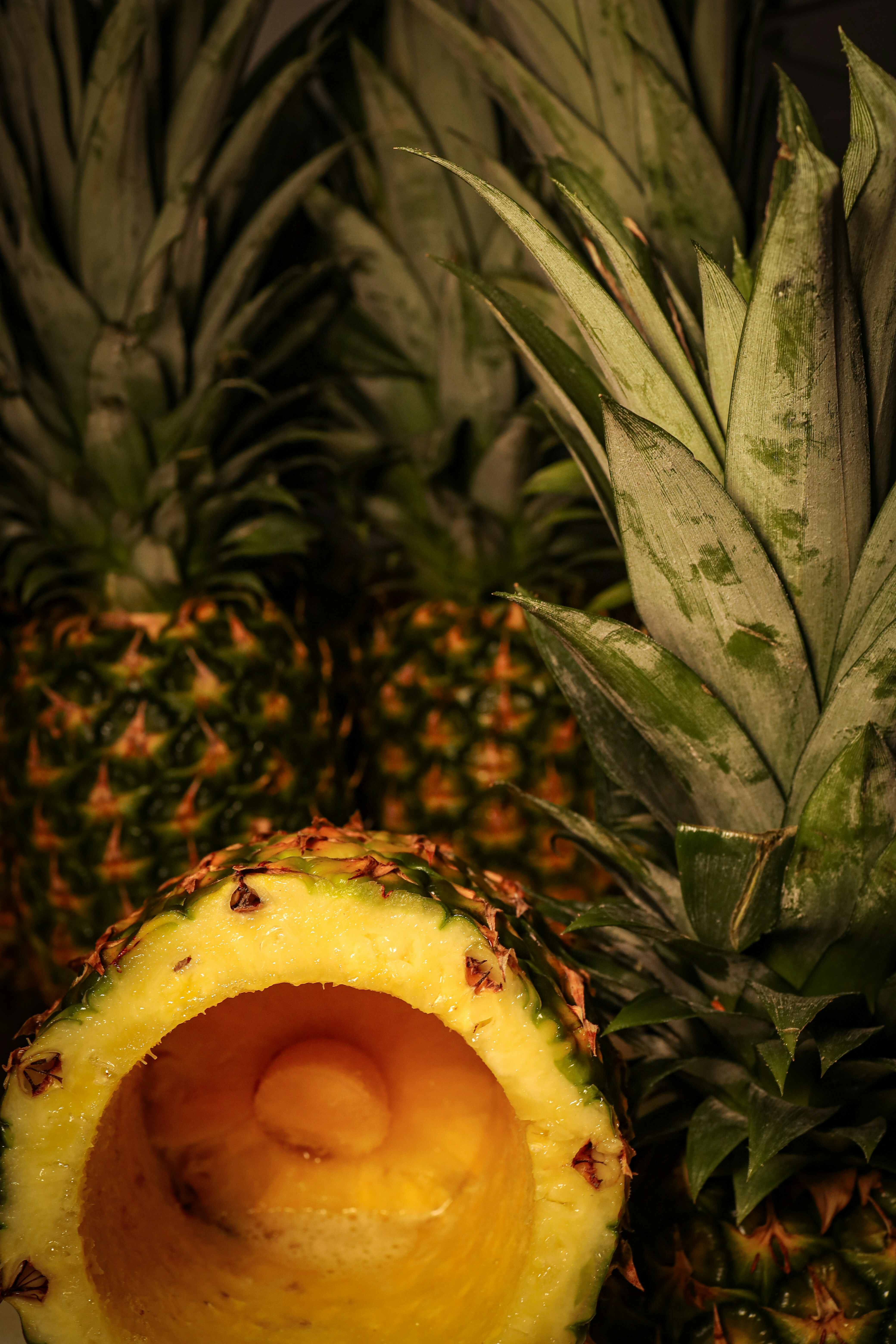Fresh pineapple cross-section showing golden yellow flesh, tropical green leaves, bright airy natural light