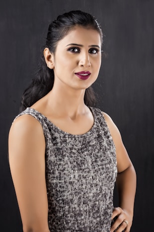 A model wearing a flowing black dress with golden accents, posing confidently.