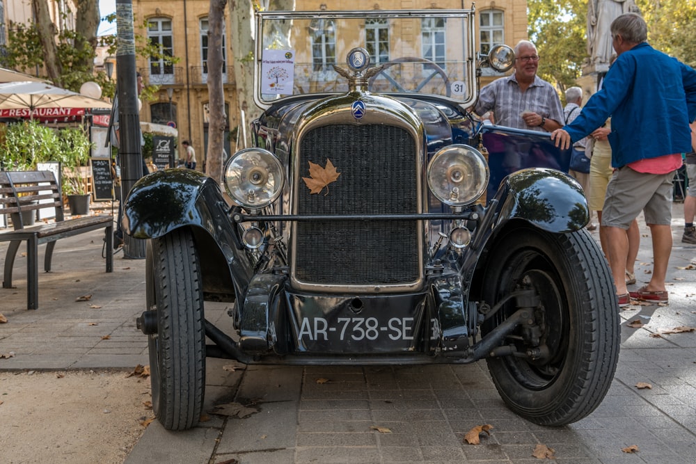 black vintage car parked beside brown wooden building during daytime