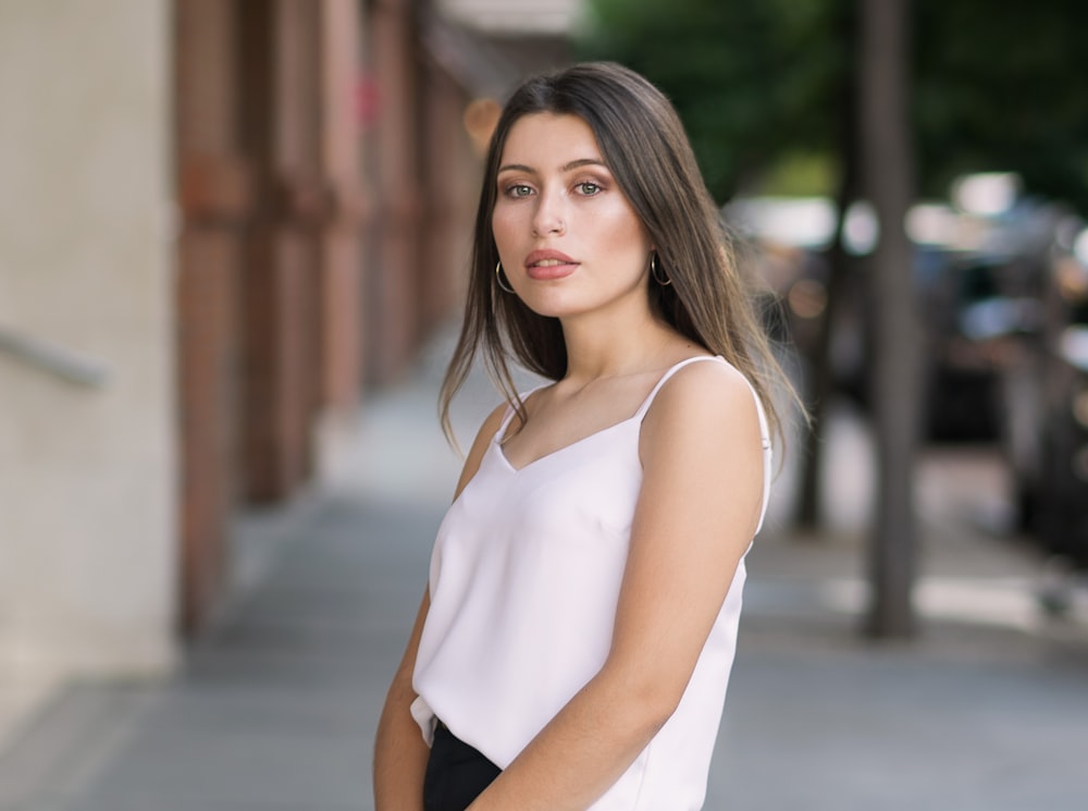 woman in white tank top standing on road during daytime