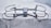 A sleek, modern drone sits on a concrete surface, equipped with a robust frame and four propellers. It appears to be designed for stability and efficiency, with aerodynamic features and a sturdy build. The drone's color seamlessly blends with its industrial setting.