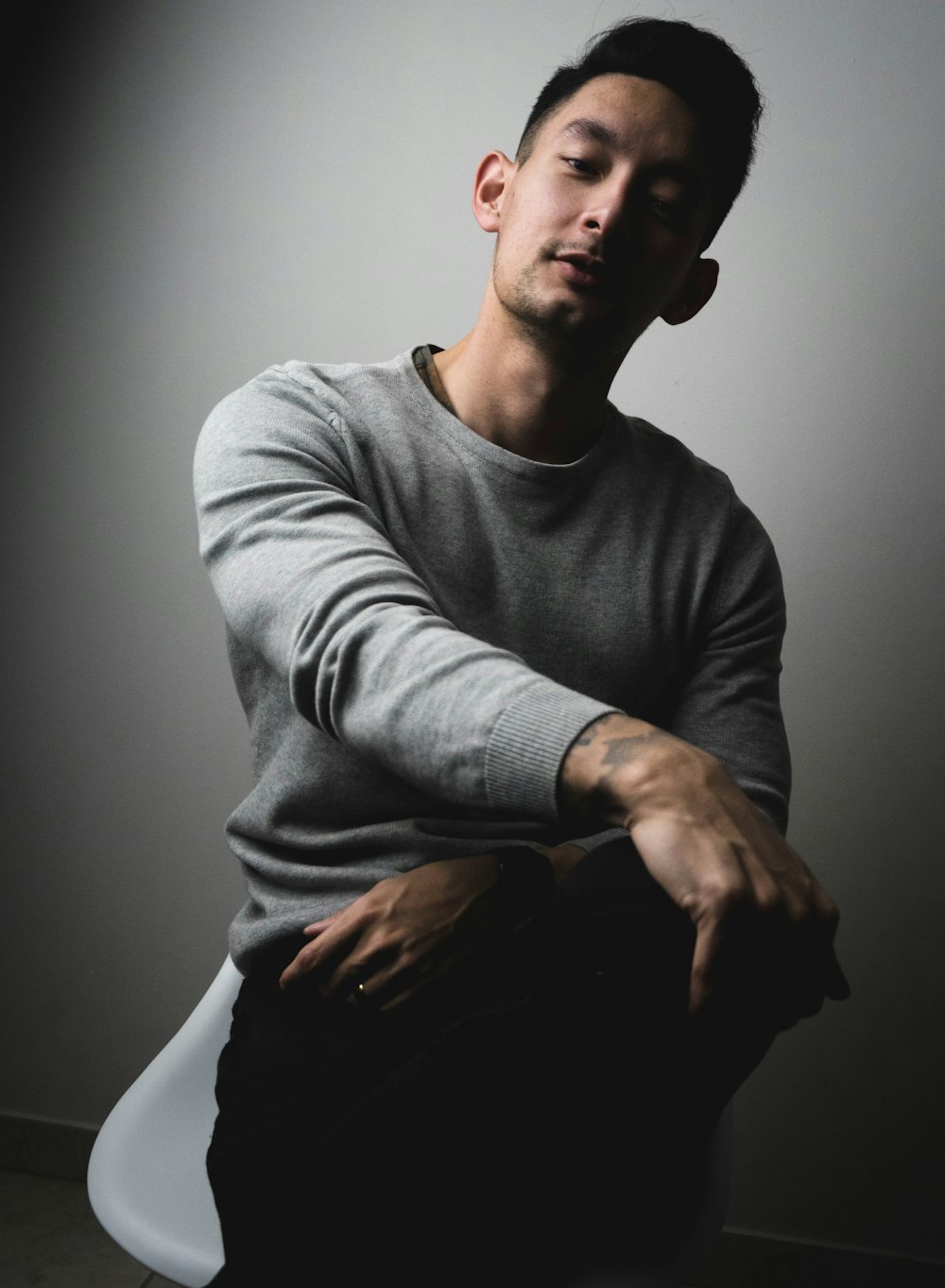 man in gray long sleeve shirt and black pants sitting on black chair