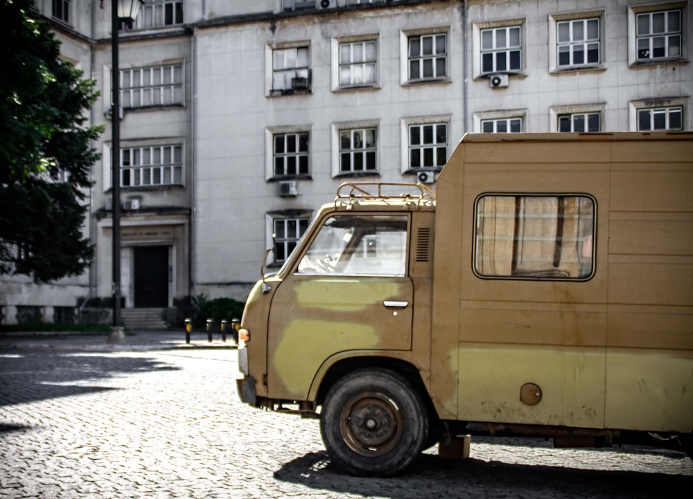 yellow van parked beside white concrete building during daytime