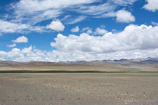 Wide shot of the open land under a bright blue sky with scattered clouds