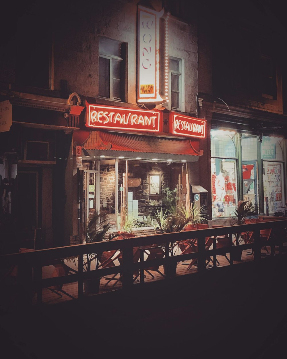 brown wooden chairs and tables in front of store during night time
