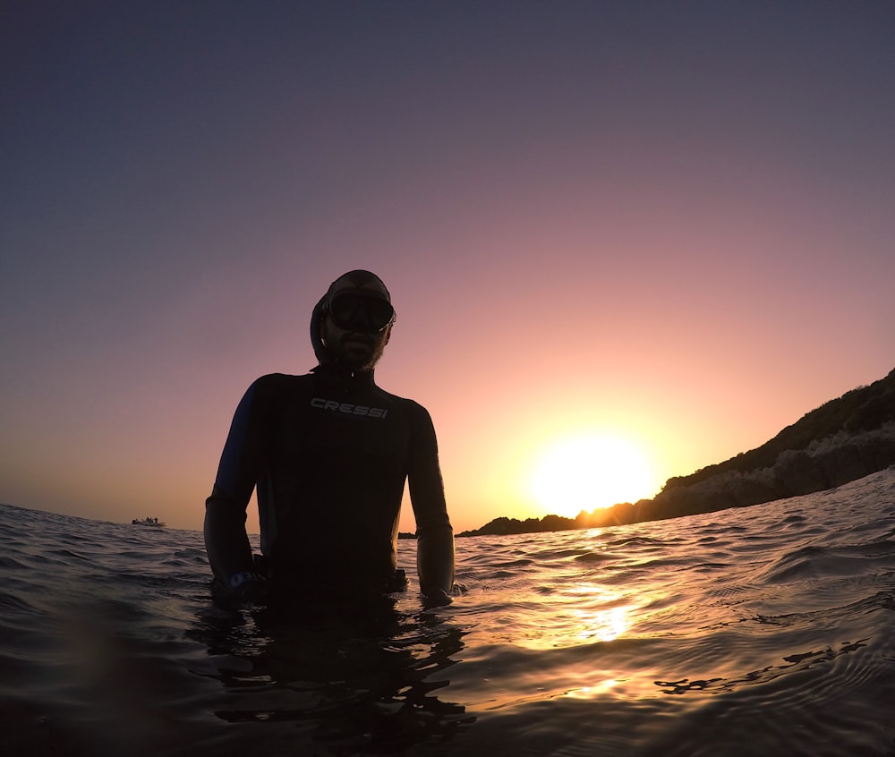 man in black tank top standing on water during sunset