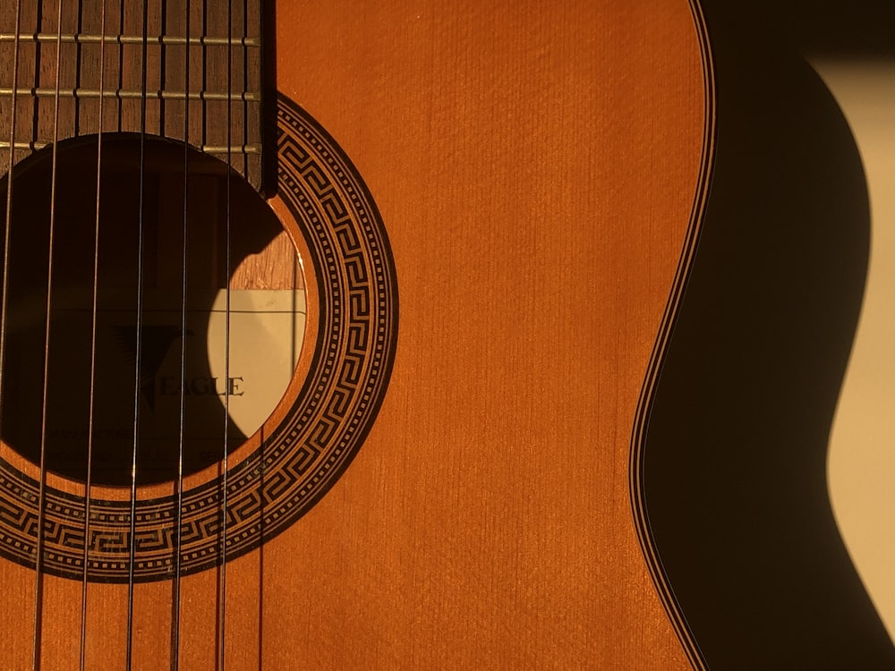 brown acoustic guitar on white textile