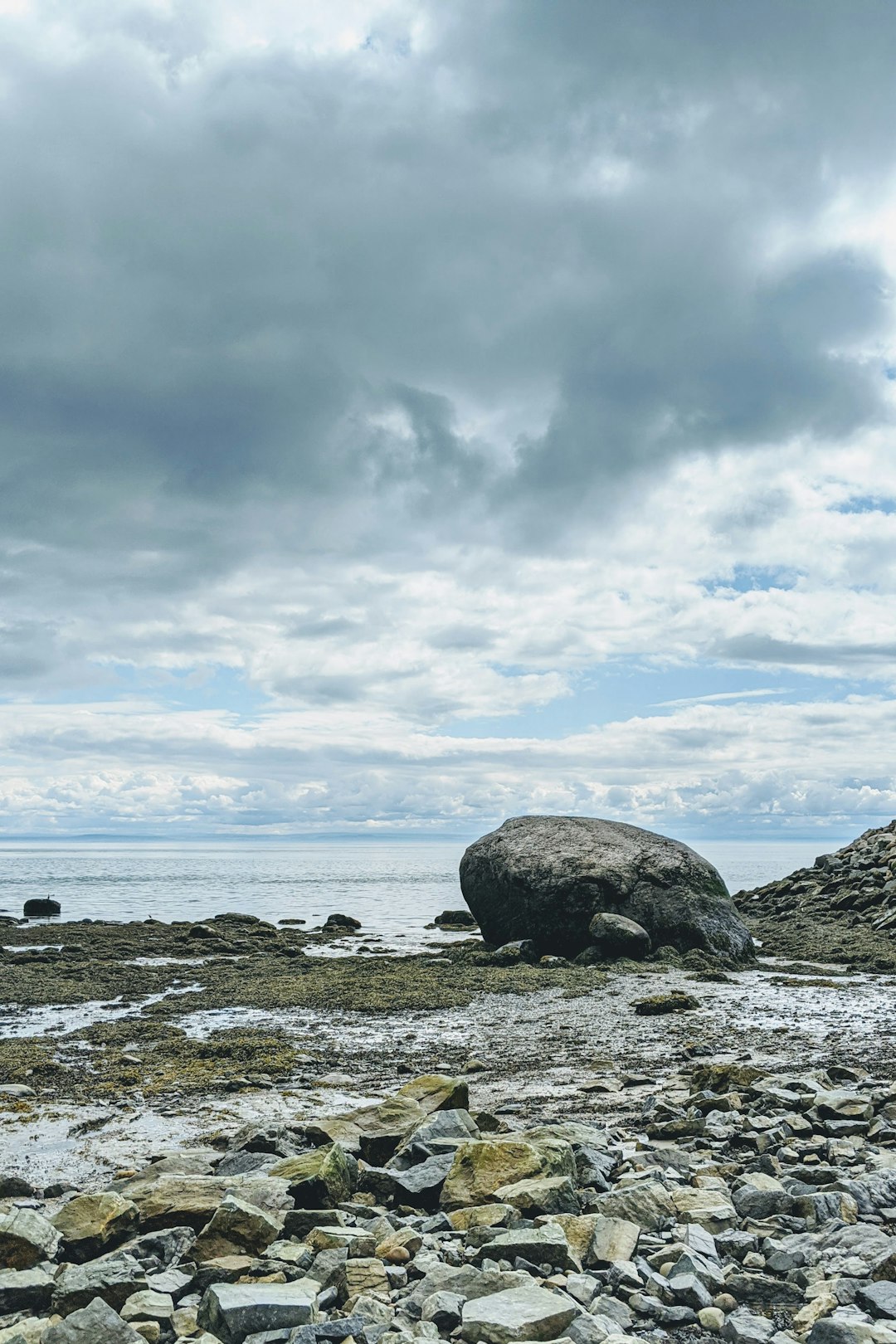 gray rock formation on sea shore under white clouds and blue sky during daytime