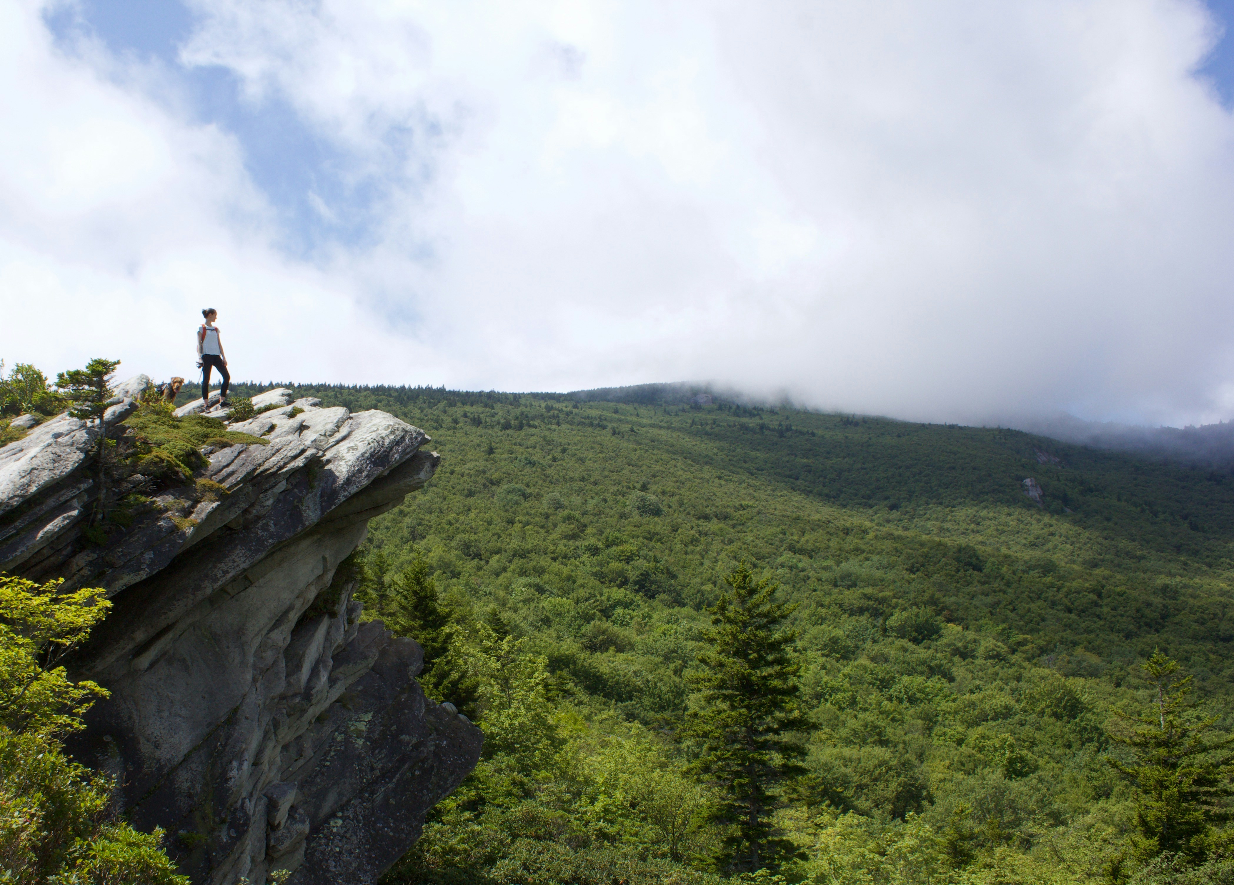 man in black shirt standing on rock formation during daytime, 