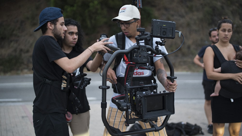 man in black t-shirt and white cap holding black video camera