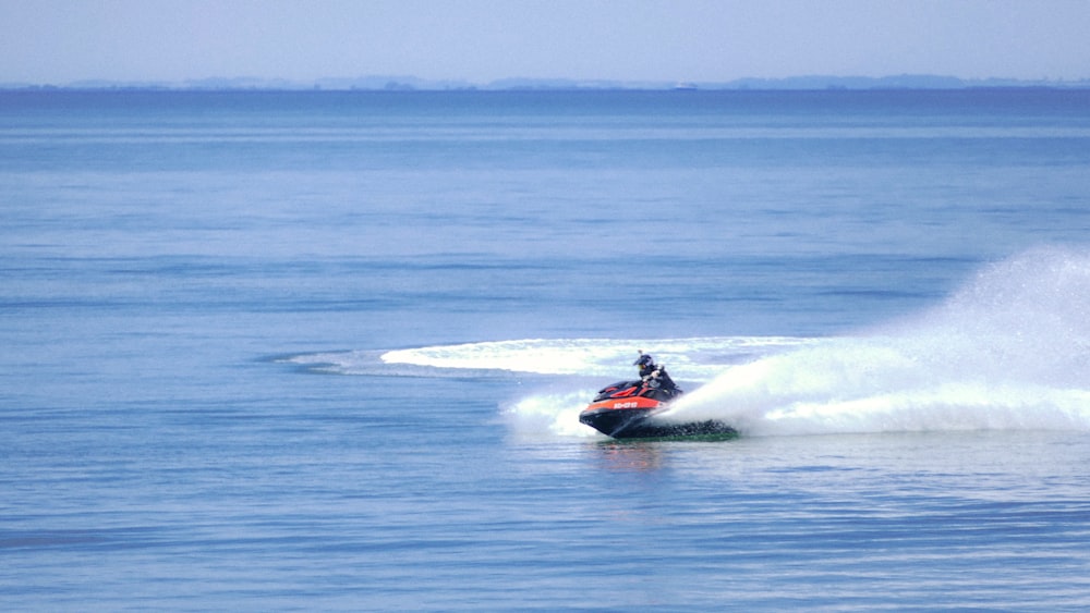 red and white personal watercraft on sea during daytime