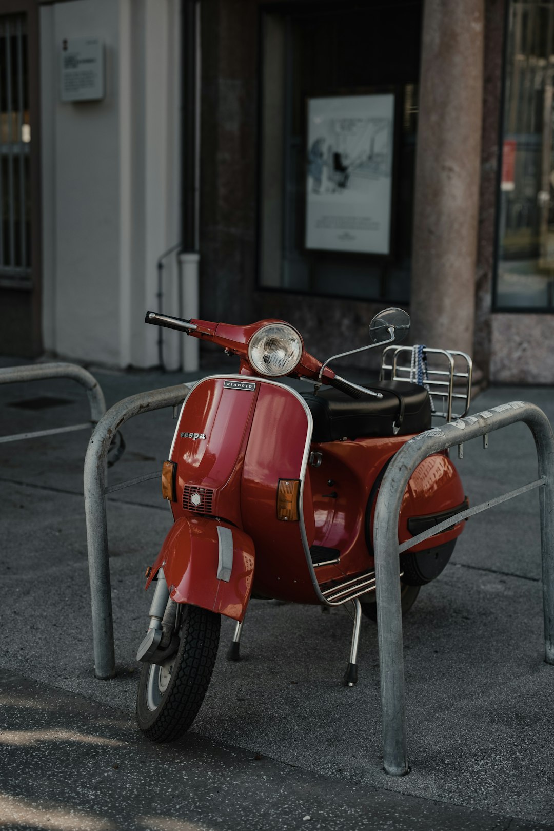 red and black motor scooter parked on sidewalk during daytime