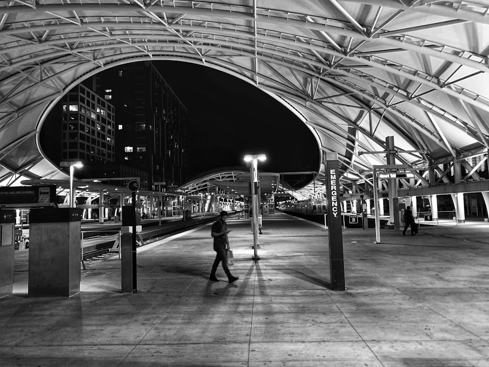 grayscale photo of man walking on the street