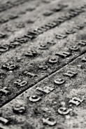 Hands carefully restoring worn inscriptions on a stone memorial in natural light.