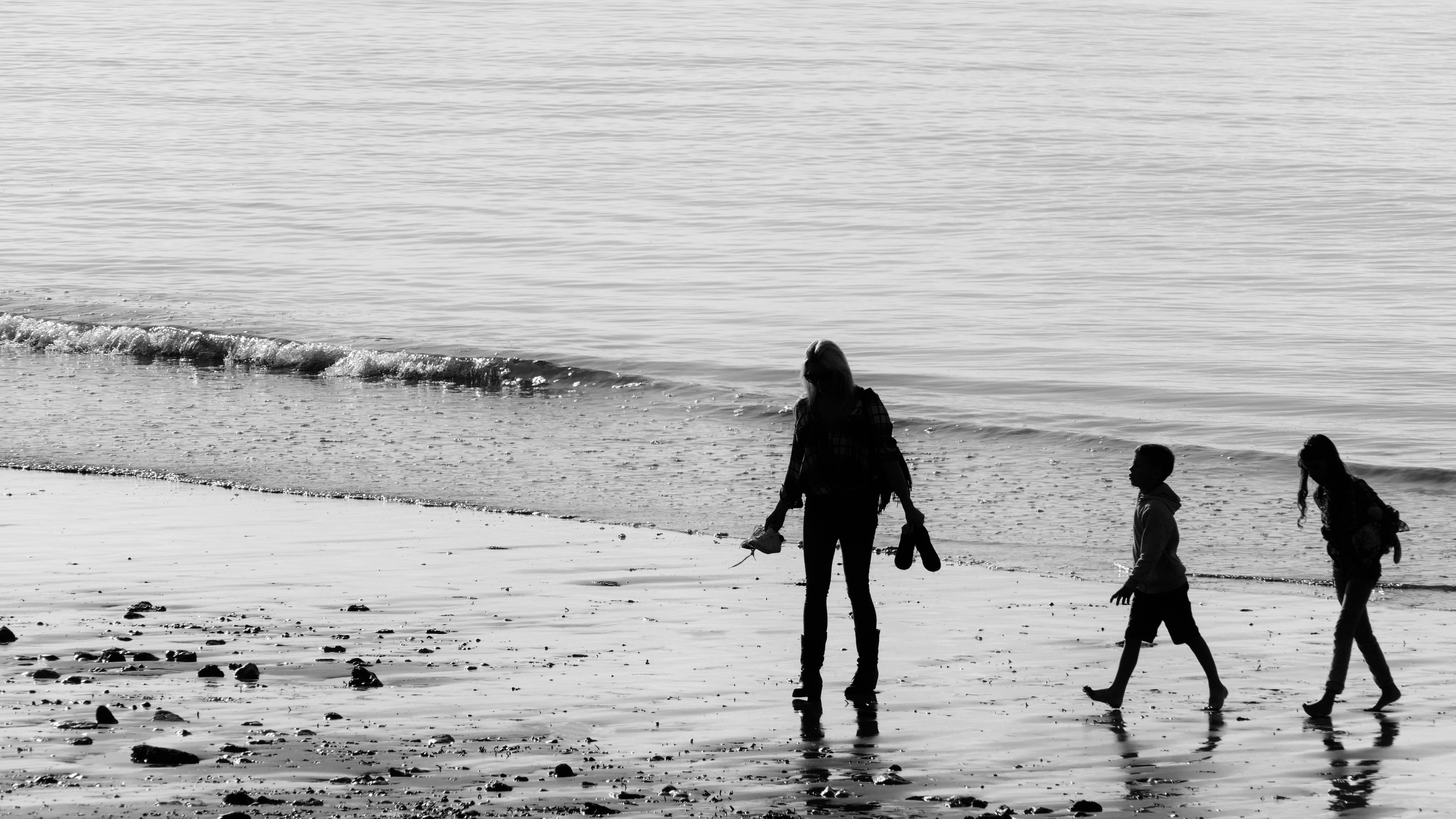 silhouette of woman walking on beach during daytime
