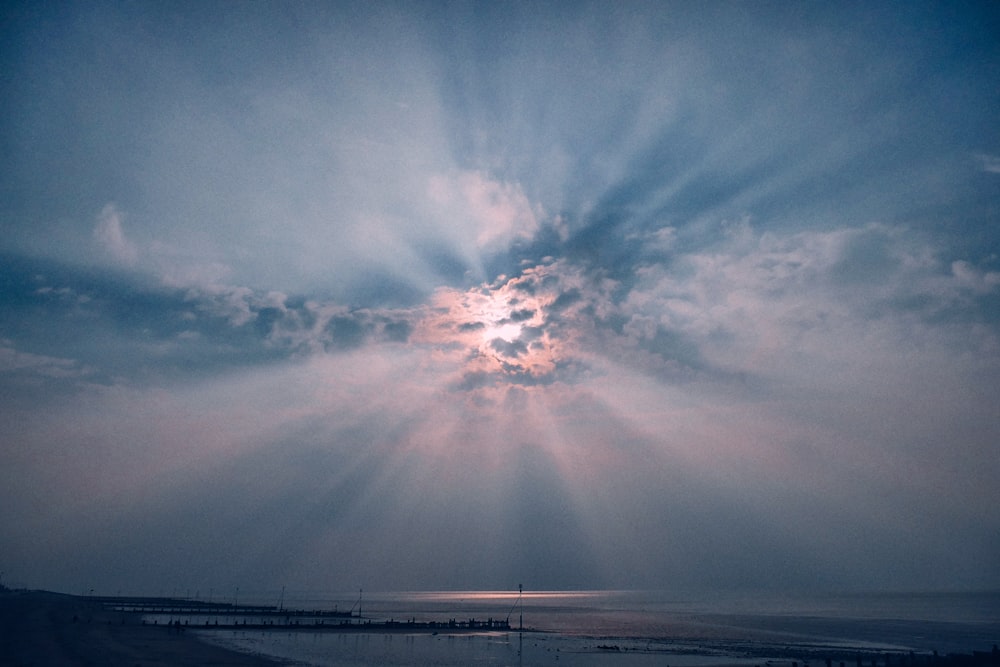 sun rays over sea under white clouds