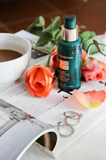 Close-up of a delicate serum bottle resting on soft rose petals with warm cream background.