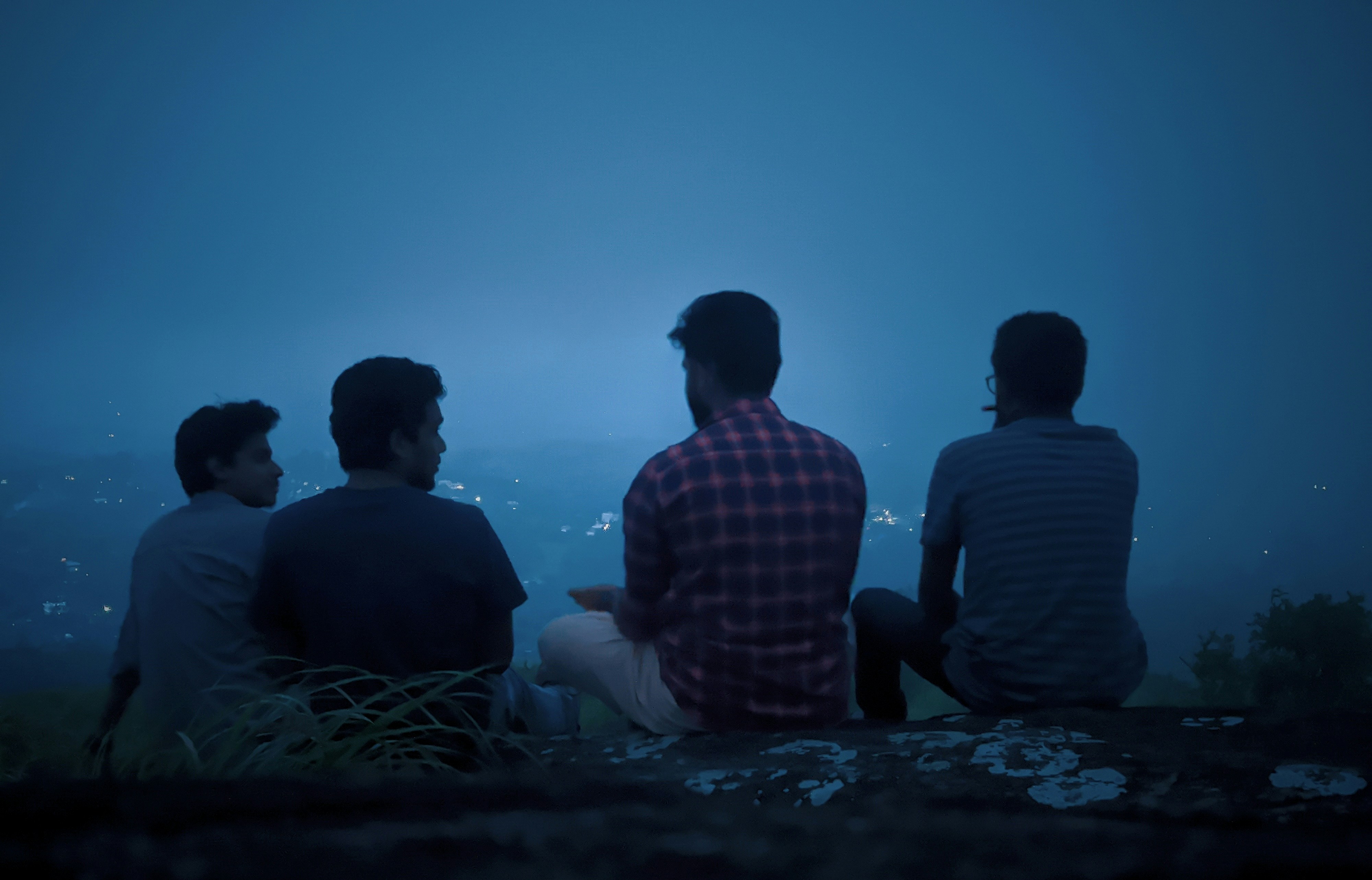 Happy group of friends celebrating on a hilltop at sunset with city lights below