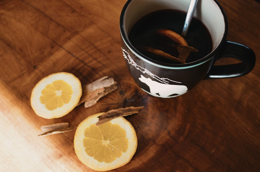 sliced lemon beside black ceramic mug