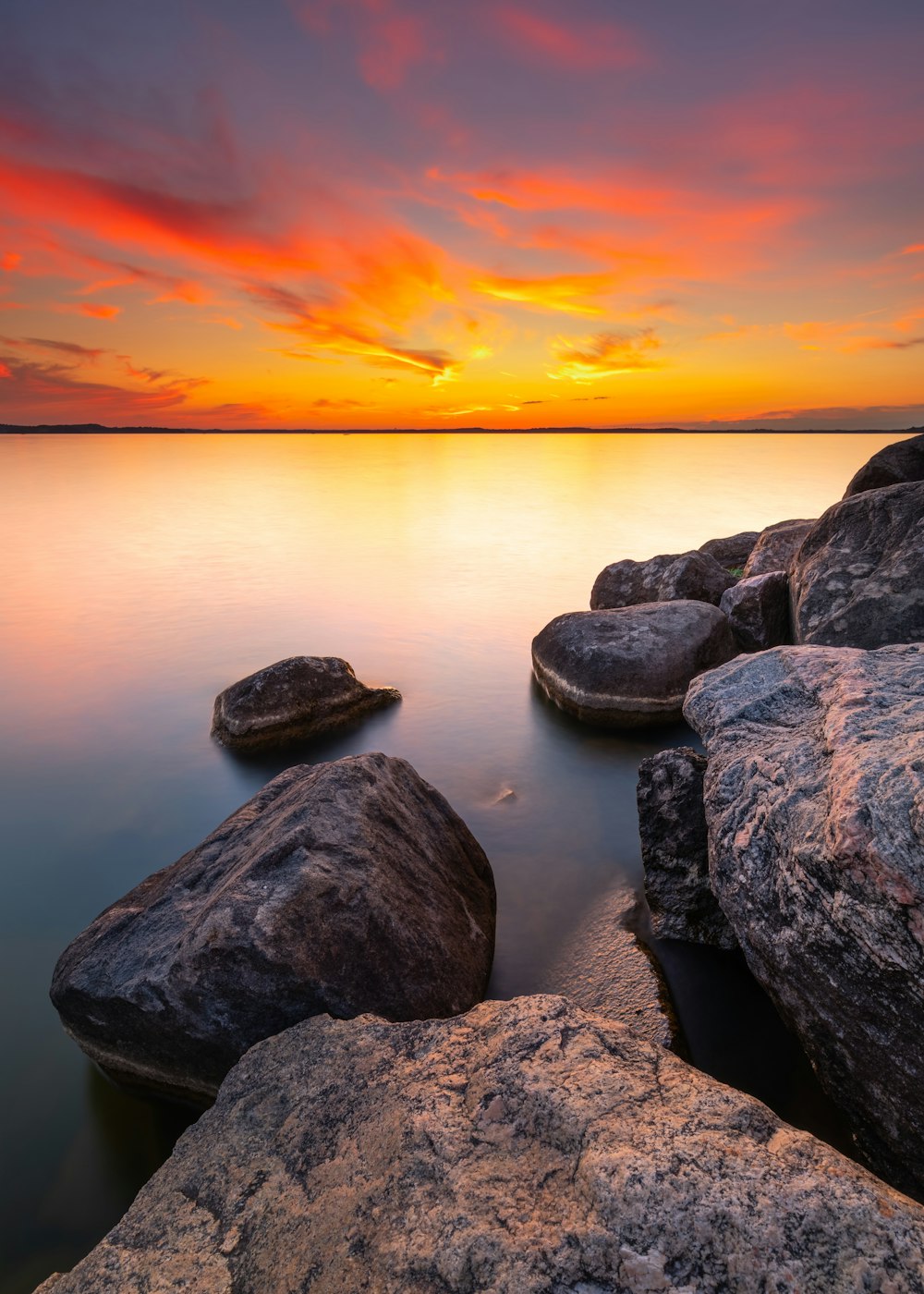 日没時の水域の灰色の岩