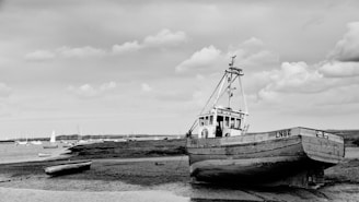 grayscale photo of boat on beach