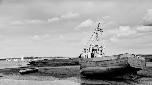 grayscale photo of boat on beach