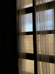 View of the room’s large window with sheer curtains.