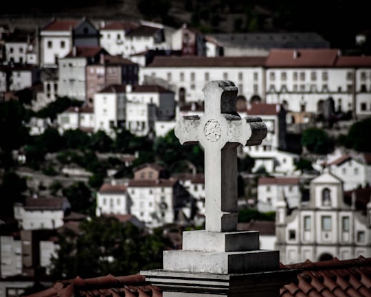 white concrete cross on top of building in Universidade de Coimbra Portugal