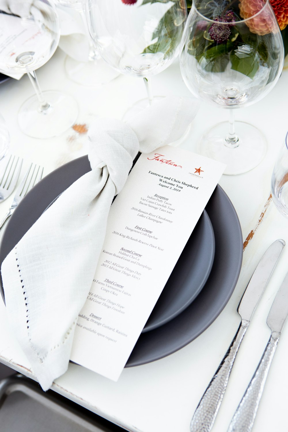 white printer paper beside clear wine glass on white table cloth