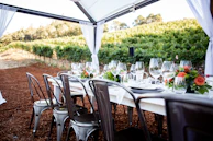 A rustic wooden table set for an intimate dinner on the villa’s terrace, overlooking rolling vineyards at sunset.