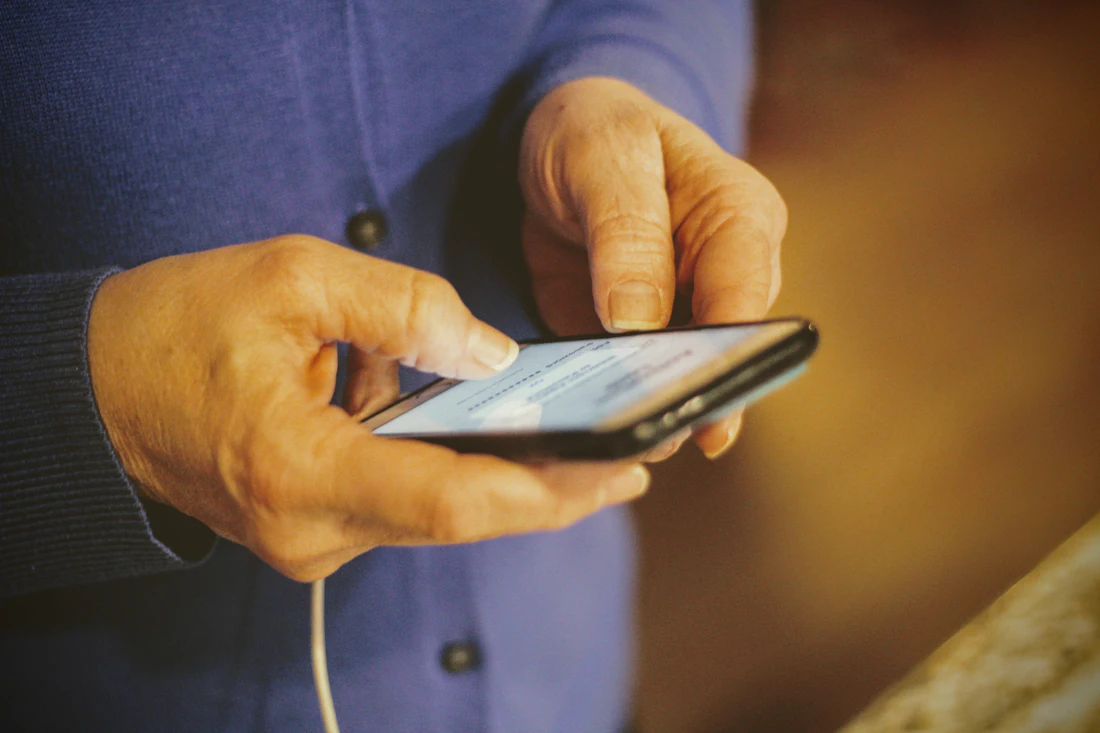 A person holding a phone, ready to call for help on behalf of a resident