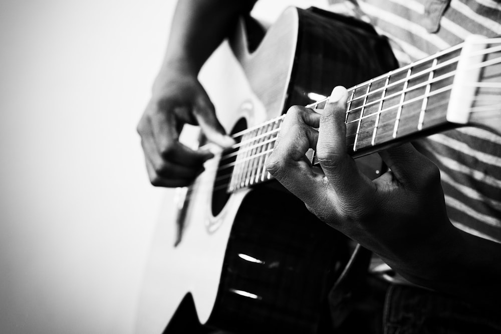 grayscale photo of person playing acoustic guitar