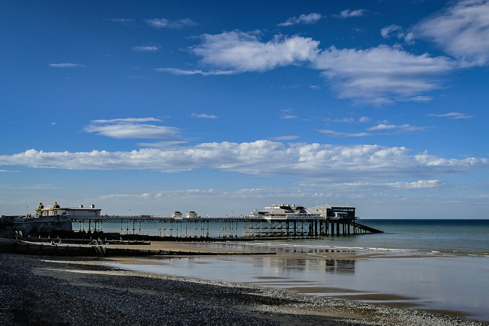 Muelle de madera blanco y marrón en el mar bajo el cielo azul durante el día