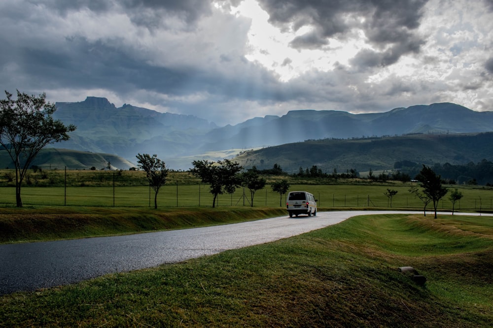 Van blanc sur la route sous un ciel nuageux pendant la journée