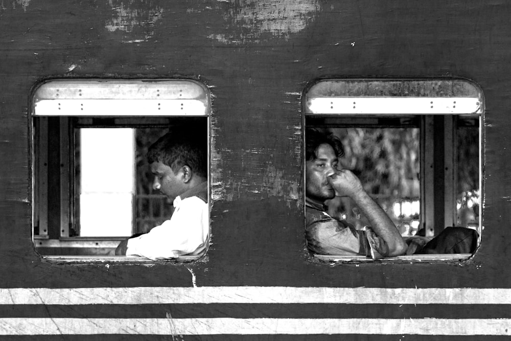 grayscale photo of man and woman sitting on train