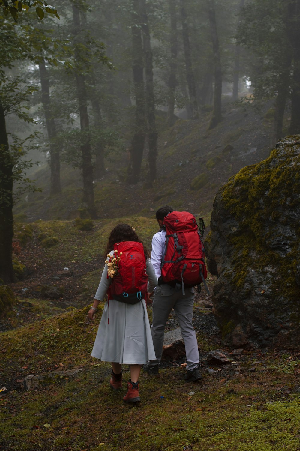 couple in red and black jackets walking on pathway