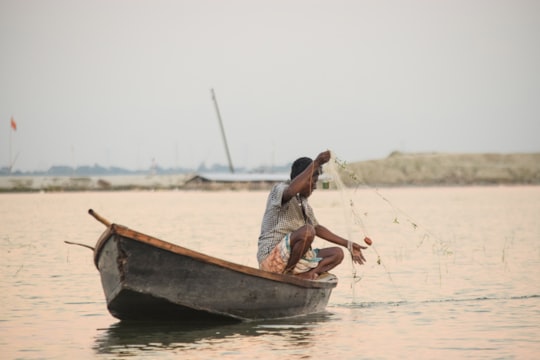 woman in white tank top sitting on brown boat during daytime in Madhabdi Bangladesh