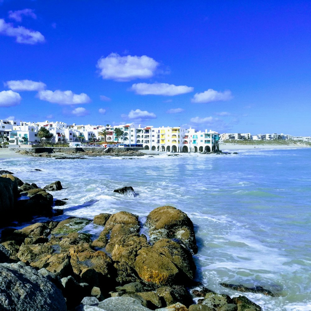 edifício de concreto branco e marrom perto do mar sob o céu azul durante o dia