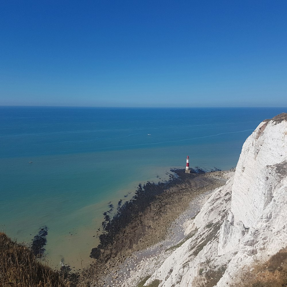 person standing on cliff near body of water during daytime