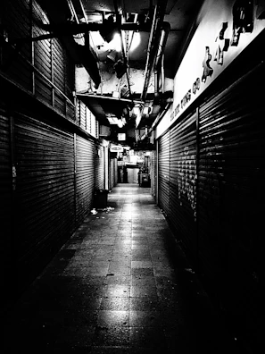 An eerie abandoned alleyway with flickering street lamps casting long shadows.