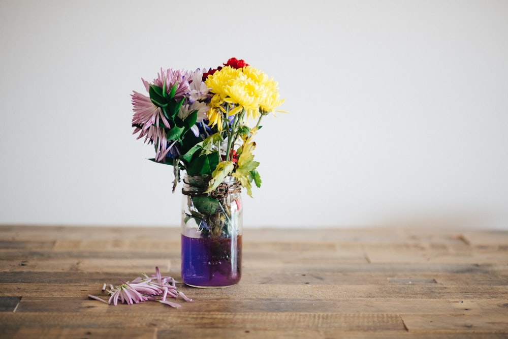 yellow and white flowers in clear glass vase