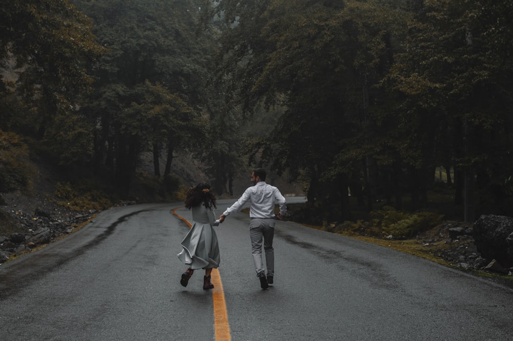 man in white jacket and black pants walking on gray asphalt road during daytime