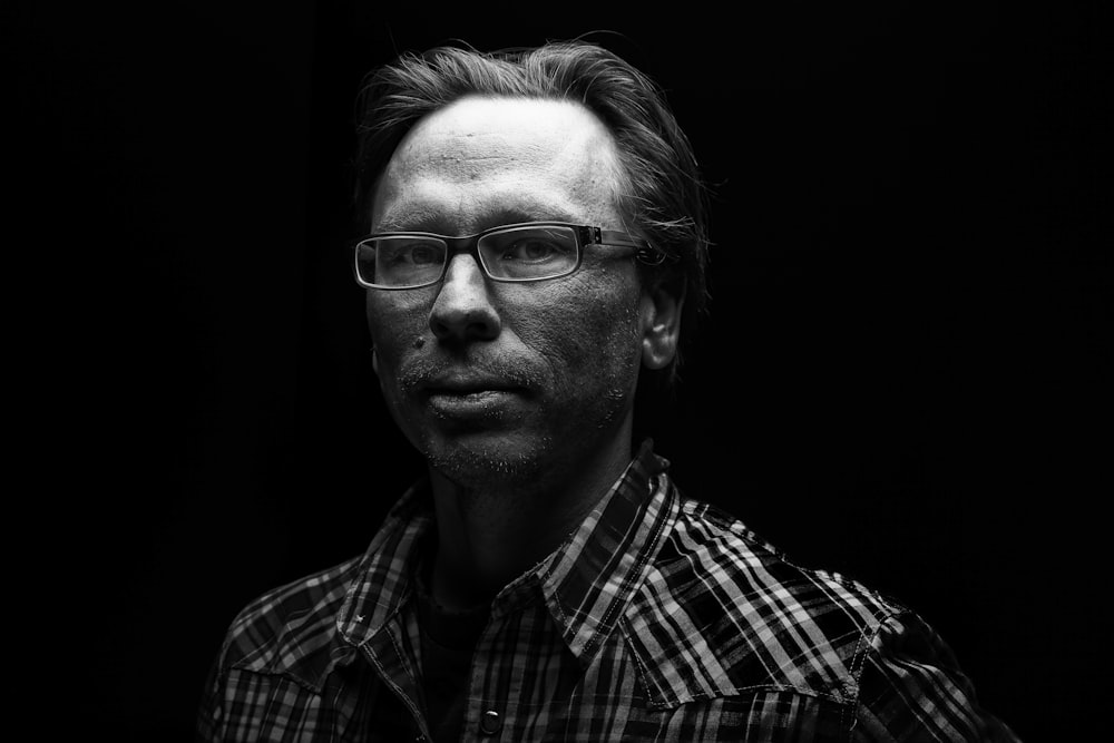 homme en chemise boutonnée à carreaux noir et blanc portant des lunettes