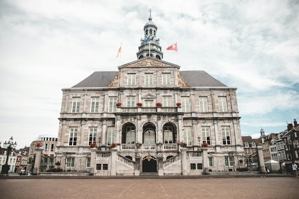 White and brown concrete building under white clouds during daytime — Maastricht, Netherlands
