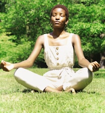woman in white tank top sitting on green grass field during daytime
